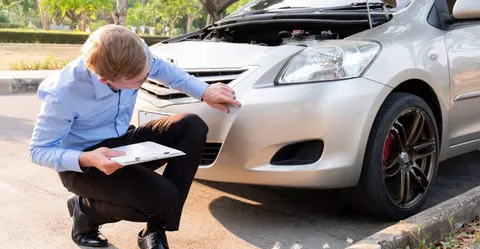 An insurance agent assesses the damage to the car